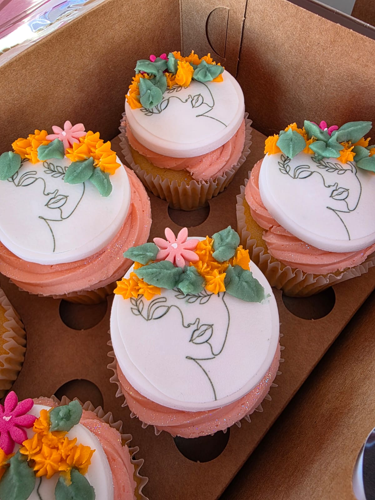 Close-up of hand-piped Women's Day cupcakes with blush buttercream and line-art faces
